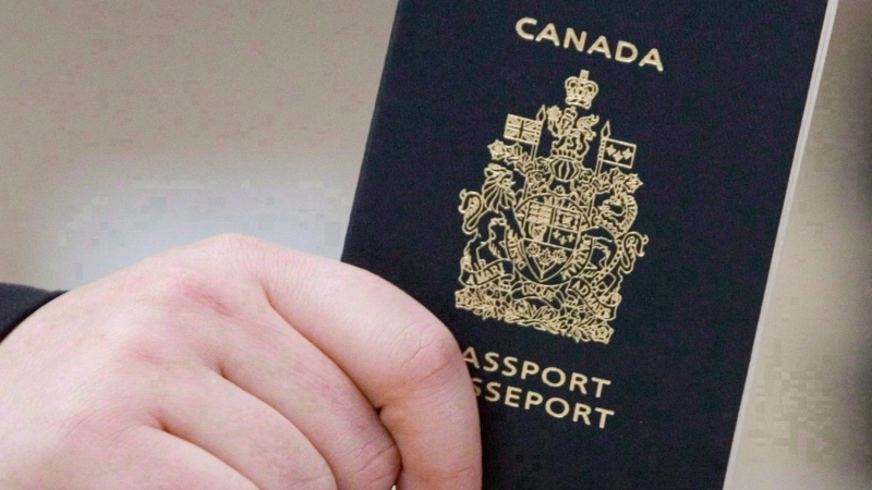 A passenger holds a Canadian passport before boarding a flight in Ottawa on Jan 23, 2007. THE CANADIAN PRESS/Tom Hanson 