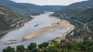 A barge passes exposed rocks and sandbanks on the river Rhine in Bacharach, Germany, Monday, Aug. 15, 2022. (Boris Roessler/dpa via AP)