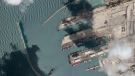 This satellite image from Planet Labs PBC shows the Sierra Leone-flagged cargo ship Razoni, centre bottom with four white cranes on its red deck, at port in Tartus, Syria, Monday, Aug. 15, 2022. (Planet Labs PBC via AP)