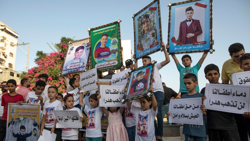 Children hold pictures of the children of Nijim family who were killed during an Israeli airstrike on cemetery on the three days war on Gaza, at Al-Faluja cemetery in Jebaliya, Tuesday, Aug. 16, 2022. (AP Photo/Fatima Shbair)