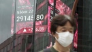 A person wearing a protective mask walks past an electronic stock board showing Japan's Nikkei 225 index at a securities firm, Aug. 17, 2022, in Tokyo. (AP Photo/Eugene Hoshiko)