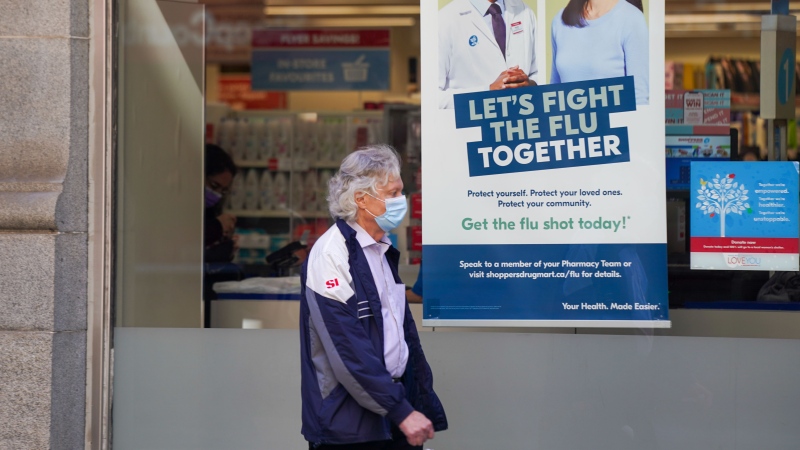 A pedestrian walks by a sign in a store window encouraging people to receive a seasonal flu shot in Toronto on Tuesday, October 19, 2021. THE CANADIAN PRESS/Evan Buhler