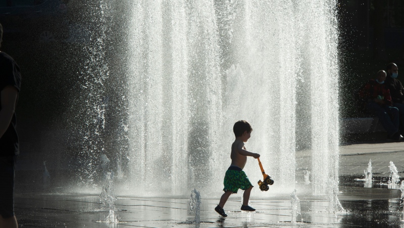 A boy beats the heat as he plays in a fountain in Montreal. (THE CANADIAN PRESS/Ryan Remiorz)