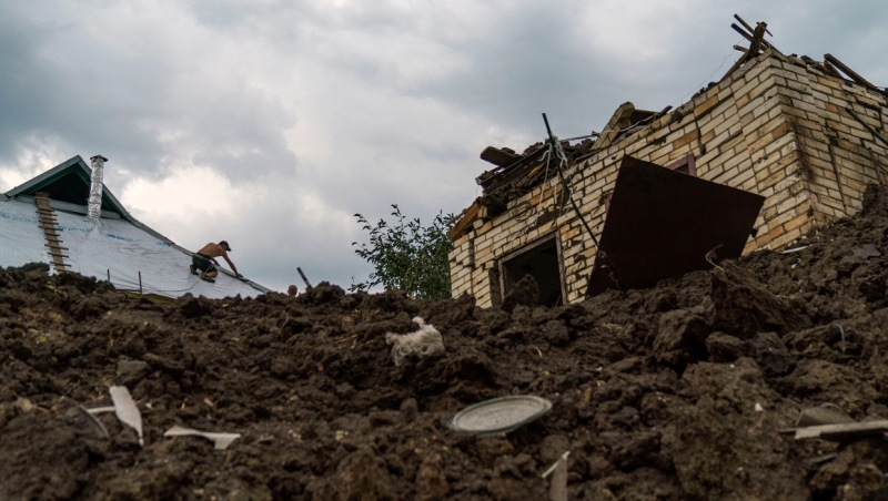 A worker repairing a roof is seen from inside a crater Thursday, Aug. 18, 2022, from a rocket strike yesterday in Druzhkivka, Donetsk region, eastern Ukraine, as Russian shelling continued to hit towns and villages in Donetsk province, regional officials said. (AP Photo/David Goldman)