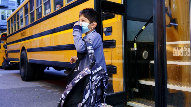 A student adjusts his protective mask as he walks off the bus at the Bancroft Elementary School as students go back to school in Montreal, on Monday, August 31, 2020. THE CANADIAN PRESS/Paul Chiasson