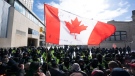 A Canadian flag is held up by a protester as police move the line up as they work to end a protest, which started in opposition to mandatory COVID-19 vaccine mandates and grew into a broader anti-government demonstration and occupation, in Ottawa, Feb. 18, 2022. THE CANADIAN PRESS/Adrian Wyld
