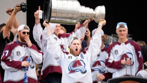Colorado Avalanche center Nathan MacKinnon lifts the Stanley Cup during a rally outside the City/County Building for the NHL hockey champions after a parade through the streets of downtown Denver, Thursday, June 30, 2022. (AP Photo/David Zalubowski) 