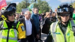 Benoit Charette, centre, outgoing environment minister and CAQ candidate in the upcoming Quebec election is escorted by police away from a climate change march in Montreal, Friday, Sept. 23, 2022. THE CANADIAN PRESS/Graham Hughes