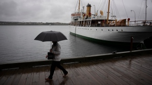 A pedestrian shields themselves with an umbrella while walking along the Halifax waterfront as rain falls ahead of Hurricane Fiona making landfall in Halifax, Friday, Sept. 23, 2022. (THE CANADIAN PRESS/Darren Calabrese)