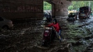 A man pushes his scooter through a waterlogged road after it rained in New Delhi, India, Thursday, Sept. 22, 2022. (AP Photo/Altaf Qadri)
