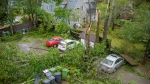 Fallen trees behind houses are shown in Charlottetown as post-tropical storm Fiona, one of the strongest storms to ever strike Eastern Canada, continued to lash the region on Saturday, Sept. 24, 2022. THE CANADIAN PRESS/Brian McInnis
