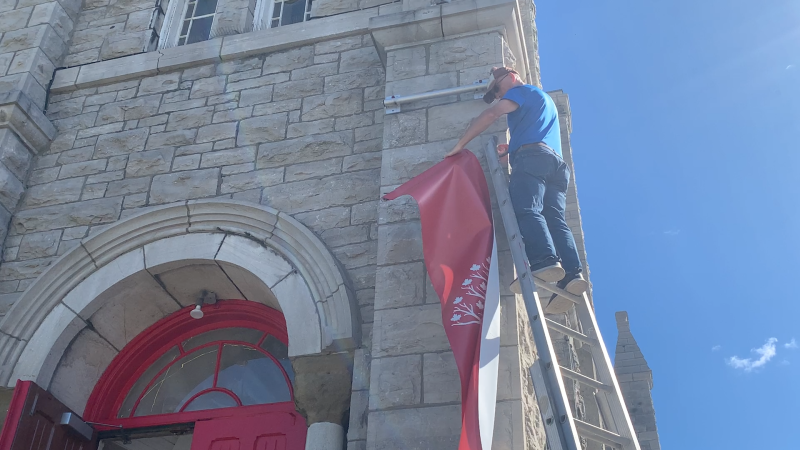 The United People of Canada's banner is removed from St. Brigid's church in Ottawa's Lowertown neighbourhood on Saturday. (Jackie Perez/CTV News Ottawa) 