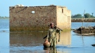 A man carries some belongings as he wades through floodwaters in Jaffarabad, a flood-hit district of Baluchistan province, Pakistan on Sept. 19, 2022. Pakistan said Monday there have been no fatalities for the past three days from the deadly floods that engulfed the country since mid-June, a hopeful sign that the nation is turning a corner on the disaster. (AP Photo/Zahid Hussain)