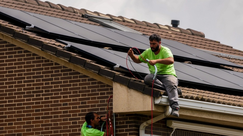 Workers install solar planers on the roof of a house in Rivas Vaciamadrid, Spain, on Sept. 15, 2022. (Manu Fernandez / AP)