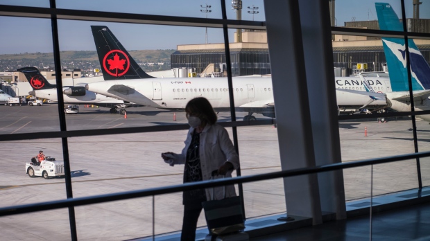 A passenger walks past Air Canada and WestJet planes at Calgary International Airport in Calgary, Alta., Wednesday, Aug. 31, 2022.THE CANADIAN PRESS/Jeff McIntosh