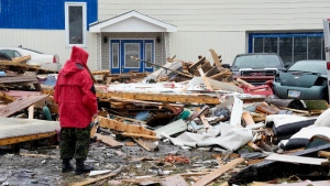 A Canadian Forces Ranger examines damage to a home in Port aux Basques, N.L., on Sept. 26, 2022. (Frank Gunn / THE CANADIAN PRESS)