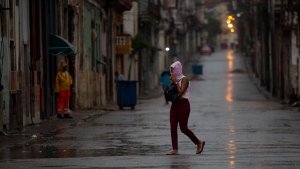 A pedestrian crosses an empty street during the passing of Hurricane Ian in Havana, Cuba, Sept. 27, 2022. (AP Photo/Ismael Francisco)