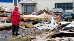 A Canadian Forces Ranger examines damage to a home in Port aux Basques, N.L., Monday, Sept. 26, 2022. Across the Maritimes, eastern Quebec and in southwestern Newfoundland, the economic impact of hurricane Fiona’s wrath is still being tallied. (THE CANADIAN PRESS/Frank Gunn)