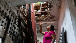 A woman points to damage in her roof, above the second story, caused by Hurricane Ian in Pinar del Rio, Cuba, Tuesday, Sept. 27, 2022.  (AP Photo/Ramon Espinosa)