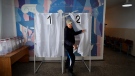 A man holds his ballot as he leaves a voting booth at a polling station during a referendum in Melitopol, Zaporizhzhia region, southern Ukraine, Tuesday, Sept. 27, 2022. (AP Photo)