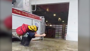 This image provided by the Naples Fire Rescue Department shows a firefighter carrying gear in water from the storm surge from Hurricane Ian on Wednesday, Sept. 28, 2022 in Naples, Fla. Hurricane Ian has made landfall in southwestern Florida as a massive Category 4 storm. (Naples Fire Department via AP)