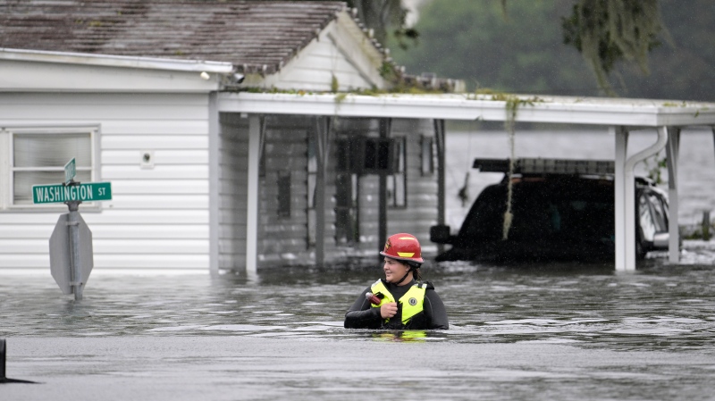 A first responder with Orange County Fire Rescue makes her way through floodwaters looking for residents of a neighbourhood needing help in the aftermath of Hurricane Ian, Thursday, Sept. 29, 2022, in Orlando, Fla. (AP Photo/Phelan M. Ebenhack)