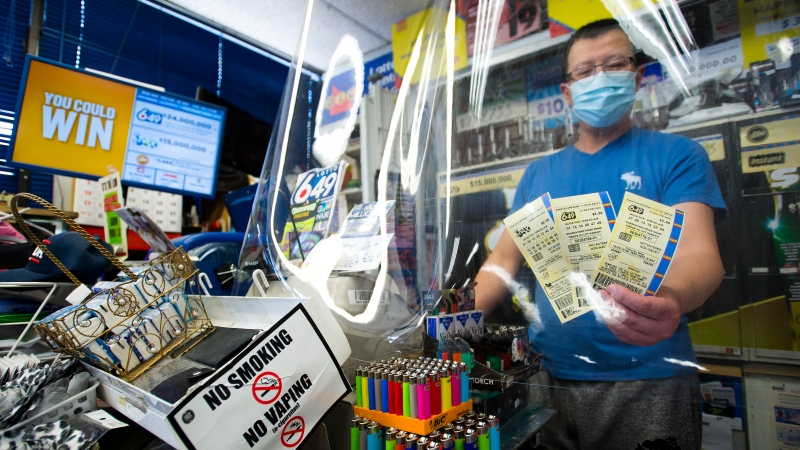A convince store owner hands OLG 649 and Lotto Max tickets at his store in Mississauga, Ont. THE CANADIAN PRESS/Nathan Denette