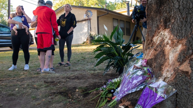 Mourners gather and lay flowers and gifts at the site of a deadly car crash during an impromptu memorial service in Lincoln, Neb., on Oct. 2, 2022. (Kenneth Ferriera / Lincoln Journal Star via AP) 