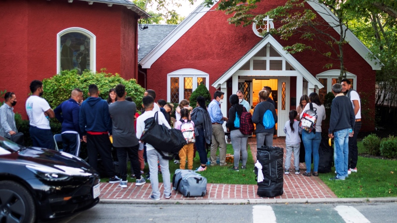 Immigrants gather with their belongings outside St. Andrews Episcopal Church, Wednesday Sept. 14, 2022, in Edgartown, Mass., on Martha's Vineyard. Florida Gov. Ron DeSantis flew two planes of immigrants to Martha's Vineyard, escalating a tactic by Republican governors to draw attention to what they consider to be the Biden administration's failed border policies. (Ray Ewing/Vineyard Gazette via AP) 