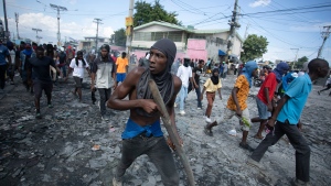 A protester carries a piece of wood simulating a weapon during a protest demanding the resignation of prime Minister Ariel Henry, in the Petion-Ville area of Port-au-Prince, Haiti, Monday, Oct. 3, 2022. (AP Photo/Odelyn Joseph)