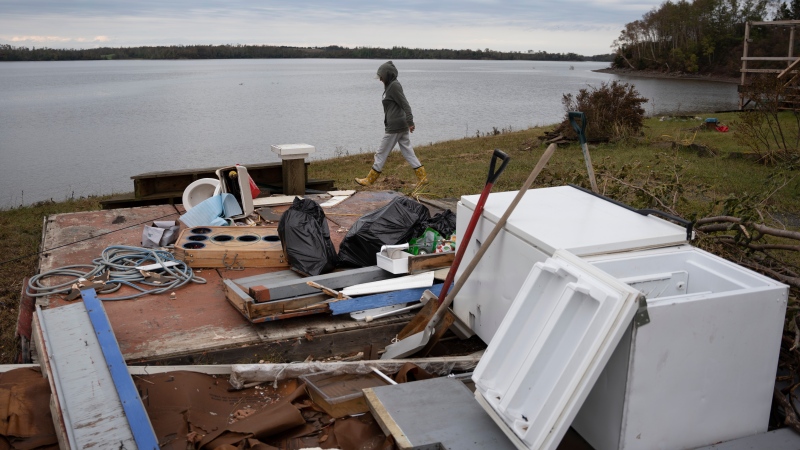 Michelle MacInnis clears debris in her yard near Merigomish in Pictou County, N.S. on Wednesday, September 28, 2022 following significant damage brought by post tropical storm Fiona. THE CANADIAN PRESS/Darren Calabrese