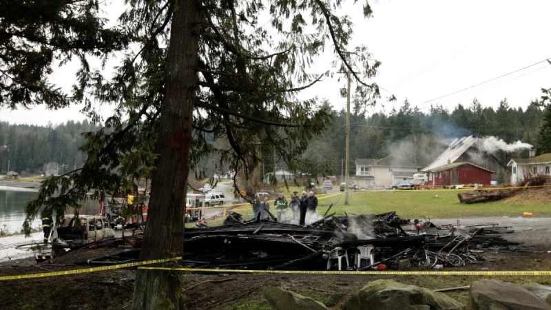 Officials including RCMP officers, a firefighter and coroner look over the smouldering remains after an early morning house fire left as many as five people dead on the Chemainus First Nations Reserve near Ladysmith, B.C., Jan. 14, 2009. THE CANADIAN PRESS/Darryl Dyck