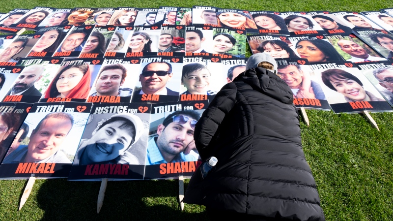 A woman places a placard with the photo of a person killed on Flight 752 during a protest on Parliament Hill, Tuesday, Oct. 4, 2022 in Ottawa. THE CANADIAN PRESS/Adrian Wyld