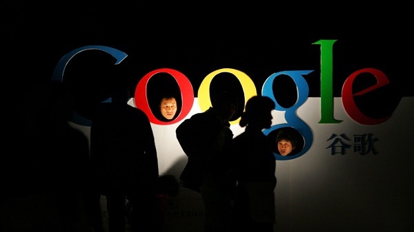 People poke their heads through a Google logo shortly after the company's debut of its Chinese Language brand name in the Beijing Hotel in Beijing, China, on April, 12, 2006. (AP / Elizabeth Dalziel)