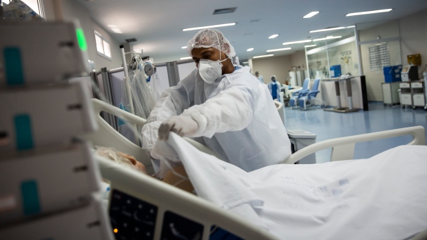 A male nurse places a blanket over a COVID-19 patient at the intensive care unit of the Dr. Ernesto Che Guevara hospital in Marica, Brazil on Jan. 26, 2022. (AP Photo/Bruna Prado)