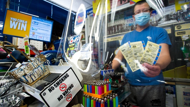 A convince store owner hands OLG 649 and Lotto Max tickets at his store during the COVID-19 pandemic in Mississauga, Ont., on Monday, May 25, 2020. Premier Doug Ford's government gives $500M loan to Ontario Lottery and Gaming. THE CANADIAN PRESS/Nathan Denette