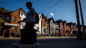 A person walks by a row of houses in Toronto on Tuesday July 12, 2022. (THE CANADIAN PRESS/Cole Burston)