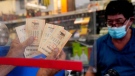 Maher Diab holds up his Powerball tickets at Bluebird Liquor, in Hawthorne, Calif., on Oct. 28, 2022. (Mark J. Terrill / AP)