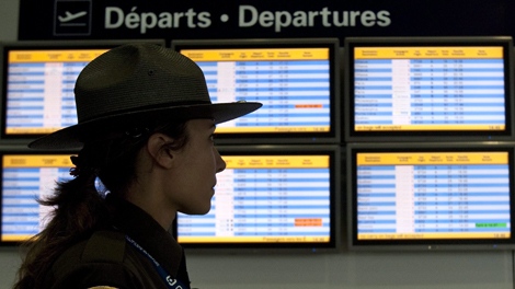 An airport security guard walks past a departures panel at the Montreal Trudeau airport in Montreal, Tuesday, Jan. 5, 2010. (Paul Chiasso / THE CANADIAN PRESS)  
