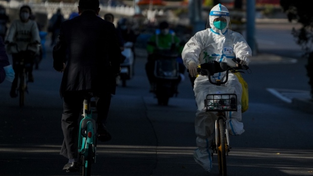 A worker in protective gear rides on a street as she heads to take COVID-19 sample from residents who have been under home quarantine in Beijing, on Nov. 3, 2022. (Andy Wong / AP) 
