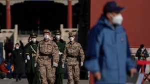 Soldiers and paramilitary policemen wearing face masks march through masked visitors at the Forbidden City in Beijing, on Nov. 13, 2022. (Andy Wong / AP) 