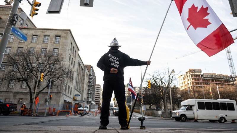 A Freedom Convoy supporter stands at the curb in front of Library and Archives Canada, the site of the Public Order Emergency Commission, in Ottawa, on Wednesday, Nov. 2, 2022. THE CANADIAN PRESS/Justin Tang 
