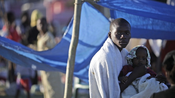 A man holds a child in a makeshift camp for earthquake survivors in the 31 Delmar neighbourhood in Port-au-Prince, Thursday, Jan. 14, 2010. Afraid to spend the night in their homes, most residents are camping out after a 7.0-magnitude earthquake struck Haiti Tuesday. (AP / Gregory Bull)