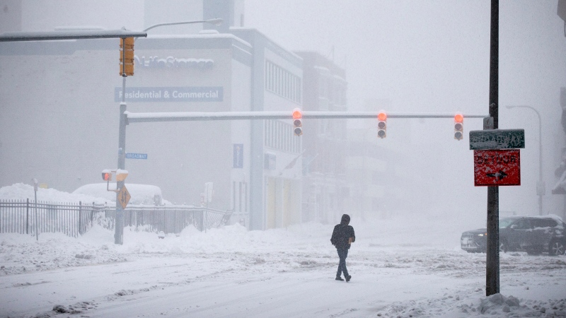 A person crosses Ellicott Street as snow falls Friday, Nov. 18, 2022, in Buffalo, N.Y. (AP Photo/Joshua Bessex)