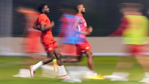Canada's star forward Alphonso Davies, left, runs in a warmup drill during practice at the World Cup in Doha, Qatar during on Monday, November 21, 2022. THE CANADIAN PRESS/Nathan Denette 