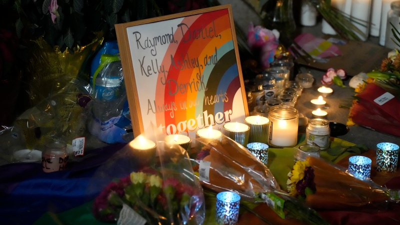 Candles stand near a sign with the names of victims of a weekend mass shooting during a vigil near the gay bar where the weekend shooting occurred, late Monday, Nov. 21, 2022, in Colorado Springs, Colo. (AP Photo/David Zalubowski) 