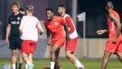 Canada star Alphonso Davies, centre, grimaces during a warmup drill at the World Cup in Doha, Qatar during on Monday, November 21, 2022. Davies, who is coming back from a hamstring strain, returned to the warmup. THE CANADIAN PRESS/Nathan Denette