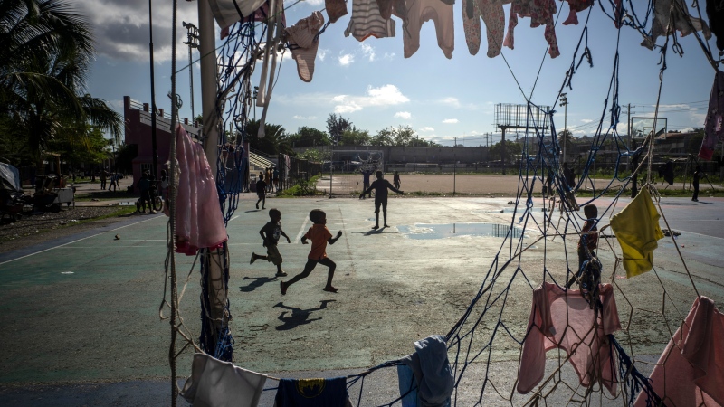 Children run past a goal post used to hang clothes at the Hugo Chavez public square transformed into a refuge for families forced to leave their homes due to clashes between armed gangs in Port-au-Prince, Haiti, Thursday, Oct. 20, 2022. (AP Photo/Ramon Espinosa)