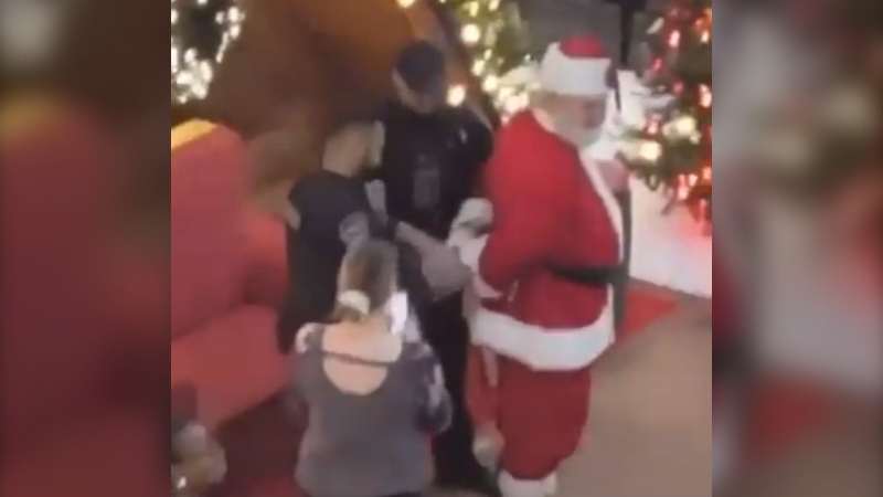 Videos and photos widely shared on social media Wednesday show the Santa Claus in CF Polo Park being handcuffed by a pair of security guards. The mall has confirmed this was a prank. (Source: Twitter)