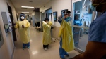 A registered nurse puts on personal protective equipment with other health-care workers before proning a COVID-19 patient in the intensive care unit at the Humber River Hospital during the COVID-19 pandemic in Toronto on January 25, 2022. (THE CANADIAN PRESS/Nathan Denette)